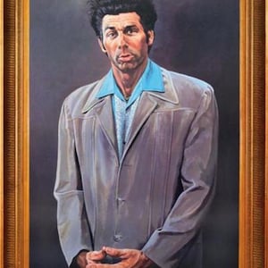 May include: A framed portrait of a man in a gray jacket over a blue shirt. The portrait is in a gold-colored wooden frame. The man has dark, curly hair and is looking directly at the viewer. The name "KRAMER" is visible at the bottom of the frame.