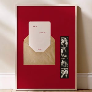 May include: Framed artwork featuring a red background with a white-bordered frame. A kraft paper envelope holds a card with red text that reads "long to, to love you, el amor." A strip of black and white photos is on the right.