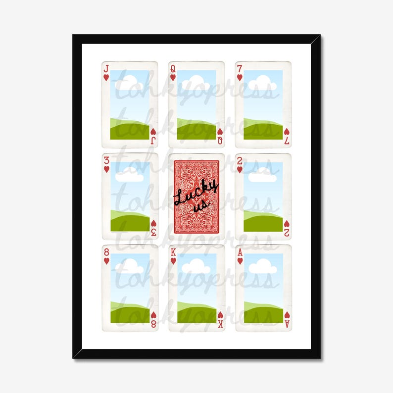 May include: A framed print featuring playing cards. The image includes a red playing card with the text "Lucky us" and other cards with landscape scenes. The cards are arranged in a grid pattern.