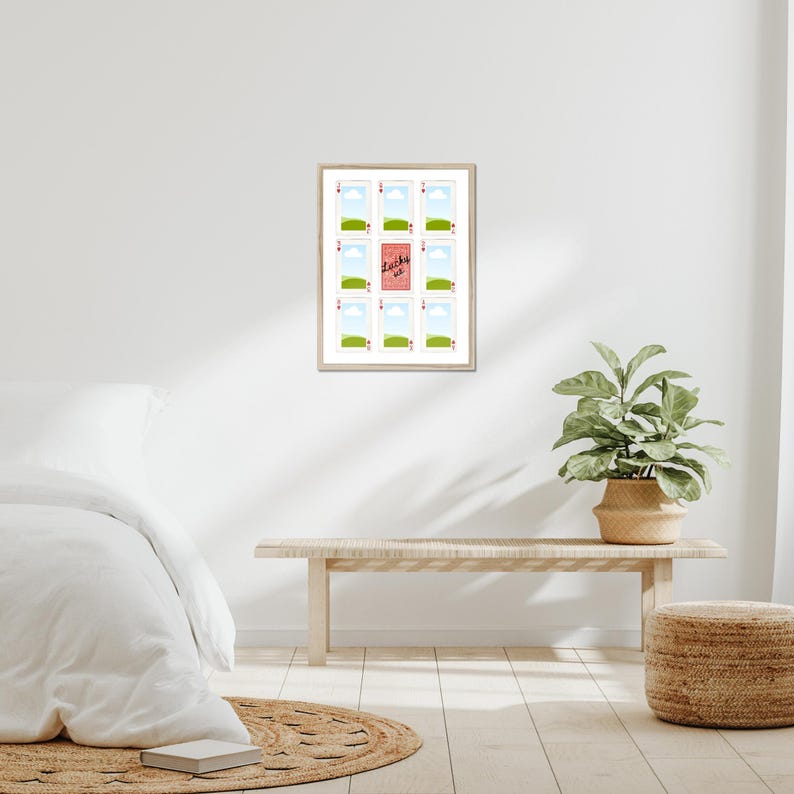 May include: A framed art print featuring a grid of twelve small images. Eleven images depict a green field and blue sky, while the central image has the text "Lucky us" on a pink background. The frame is light-colored.