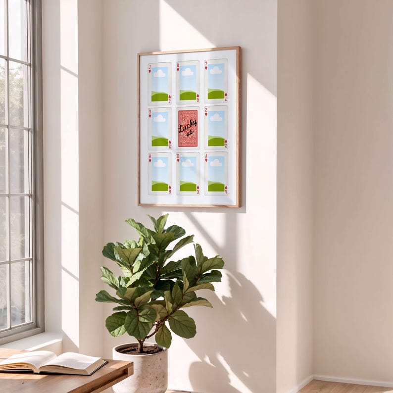 May include: A framed wall art piece featuring playing card designs. The artwork includes nine playing cards with the suits of hearts and a central card that reads "Lucky us". The frame is a light brown color.