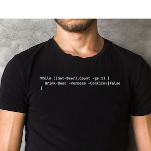 Può includere: Una maglietta nera con testo bianco che recita "While ((Get-Beer).Count -ge 1) { } Drink-Beer -Verbose -Confirm:$False"