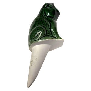 May include: A ceramic frog plant waterer. The frog is a glossy dark green color and sits atop a white, cone-shaped base. The word "JAPAN" is imprinted on the base. This garden decor item is designed to be inserted into the soil.