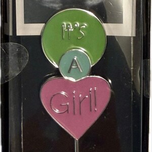 May include: A baby shower gift set with a pink heart-shaped ornament that reads "Girl!" and a green circle that reads "It's A". The set includes an ultrasound image and a "mommy 2 bee" sticker.