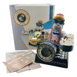May include: A novelty Gorilla Drum clock with a drummer gorilla figure wearing sunglasses, a striped vest, and a hat. The clock has a black base, a round clock face, and a drum set. The box and paperwork are visible.