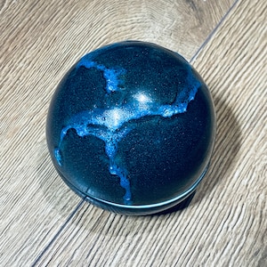 Peut inclure: Une sphère en céramique bleu foncé avec un motif de glaçure bleu clair. La glaçure a un effet craquelé, créant un aspect unique et artistique.