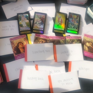 May include: A collection of tarot cards and oracle cards with handwritten notes on white cards. The cards include Temperance, Knight of Swords, The Magician, Judgement, Soul Mate, Platinum, and Mystic. The notes include "you have my attention", "gift giving", "I want to be around you", "I feel", "something new", "under a spell", "chasing", "holding back", "be here", "you deserve so much", and "whisper".