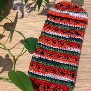 以下が含まれることがあります： 赤、緑、白、黒のストライプの入った、スイカ柄のクロシェポーチ。ポーチは糸でできており、表面はテクスチャ加工されています。