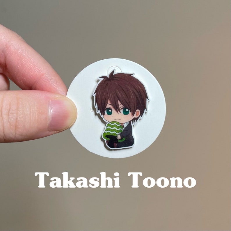 May include: A white circle sticker with a cartoon illustration of a brown-haired boy holding a green and white watermelon. The text "Takashi Toono" is printed below the sticker.