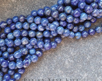 Pode incluir: Um fio de contas de lapis-lazúli azul. As contas são redondas e têm um aspecto salpicado.