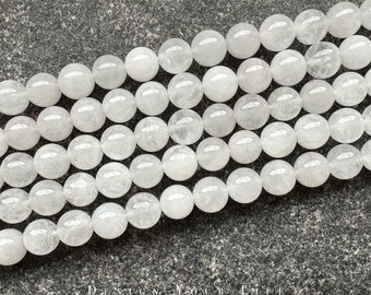 Pode incluir: Um fio de contas redondas brancas translúcidas. As contas são feitas de pedra natural e têm um aspecto ligeiramente nublado.