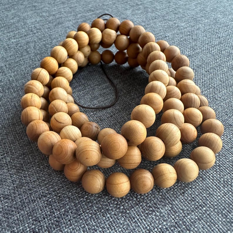 Puede incluir: Un collar de cuentas de madera marr&oacute;n claro, probablemente para la oraci&oacute;n o la meditaci&oacute;n. Las cuentas son redondas y lisas, ensartadas con un cord&oacute;n marr&oacute;n oscuro. Las cuentas son de color madera natural.