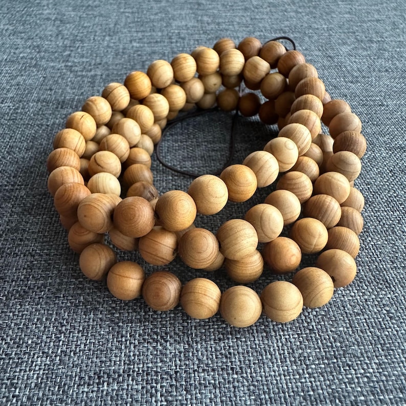 Puede incluir: Un conjunto de cuentas de madera marr&oacute;n claro, ensartadas en forma circular. Las cuentas son lisas y esf&eacute;ricas, con vetas de madera visibles. Probablemente para joyer&iacute;a o meditaci&oacute;n.
