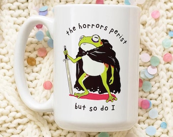 Mok grappige kikker: sarcastische koffiekopje 'The Horrors Persist'