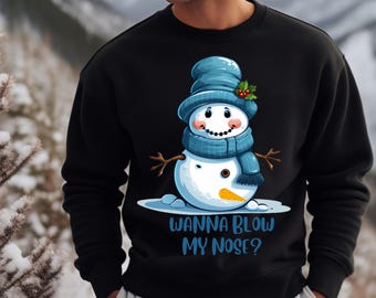May include: Black sweatshirt with a cartoon snowman wearing a blue hat and scarf. The snowman has a carrot nose and the text "Wanna Blow My Nose?" is printed below.