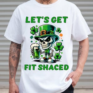 May include: White t-shirt with a green, black, and white cartoon skeleton wearing a green leprechaun hat and holding a green beer mug. The text "Let's Get Fit Shaced" is printed on the shirt.