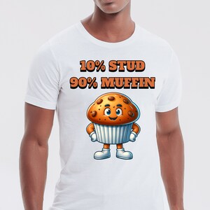 May include: White t-shirt with a cartoon muffin wearing a white paper liner and brown icing. The text "10% STUD 90% MUFFIN" is printed on the shirt.