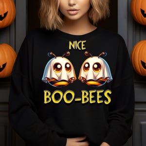 May include: Black sweatshirt with a Halloween graphic. The design shows two cartoon bees in ghost costumes, with the words "NICE" and "BOO-BEES" in yellow. The bees have large eyes. A fun, seasonal garment.