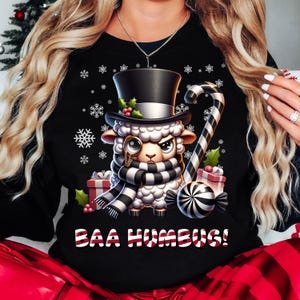 May include: Black Christmas sweater with a white sheep wearing a top hat, monocle, and scarf. The sheep is holding a candy cane and a peppermint candy. The text "BAA HUMBUG!" is printed below the sheep.