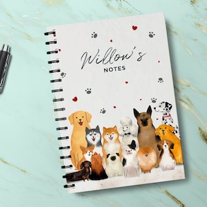 May include: A white spiral bound notebook with the text "Willow's Notes" and a colourful illustration of various dog breeds. The cover features red hearts and paw prints.
