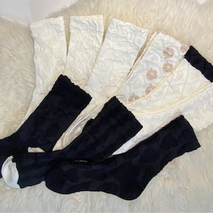 Könnte beinhalten: Ein Set mit sechs Socken, drei schwarze und drei weiße. Die weißen Socken haben ein Blumenmuster und die schwarzen Socken ein geometrisches Muster.