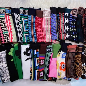 Könnte beinhalten: Eine Sammlung bunter gemusterter Socken mit verschiedenen Designs, darunter geometrische, florale und abstrakte Muster.