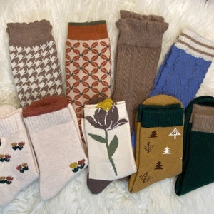 Könnte beinhalten: Sortiment von zehn bunten Socken mit verschiedenen Mustern, darunter Blumen-, geometrische und Hahnentrittmuster. Die Socken sind aus weichem, bequemem Stoff und perfekt für den Alltag.