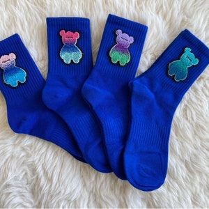 Może przedstawiać: Cztery pary niebieskich skarpet z kolorowym wzorem niedźwiedzia na każdej skarpecie.