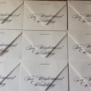 May include: Nine white envelopes arranged in a grid, each featuring the printed text "YOU ARE INVITED TO" above the script lettering "The Underwood Wedding" in black ink. The envelopes have a triangular flap design and a smooth matte finish.