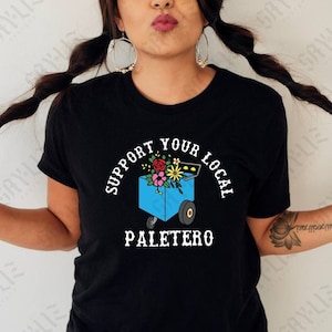 May include: A black t-shirt with a white graphic design. The graphic features a blue ice cream cart with flowers and the text "Support Your Local Paletero".