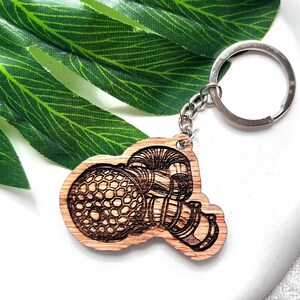 May include: A wooden keychain with a detailed laser-engraved design of a steampunk-style robot head. The keychain is attached to a silver metal key ring.