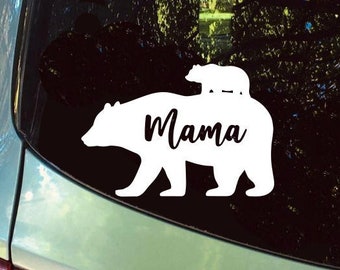 May include: White vinyl decal of a mama bear with a cub on her back. The decal says "Mama" on the bear's body.