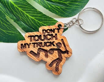 May include: Wooden keychain with the text "Don't Touch My Truck" and a stick figure holding a baseball bat. The keychain is attached to a silver key ring.