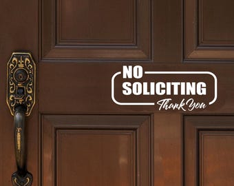 以下が含まれることがあります： 茶色の木製のドアに「NO SOLICITING Thank You」という文字が書かれた白いビニールステッカー