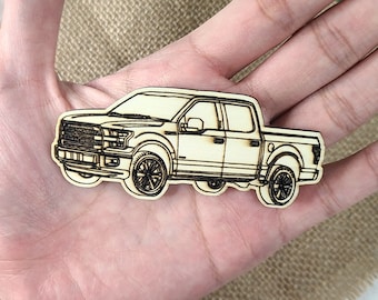 May include: A wooden cutout of a black pickup truck. The truck is detailed with a front grill, headlights, and wheels.