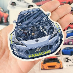 May include: A white car with a blue and black engine visible through the bonnet. The car has a black and yellow stripe on the front bumper and the words "Things won't change until we do" and "Panache" printed on the front.