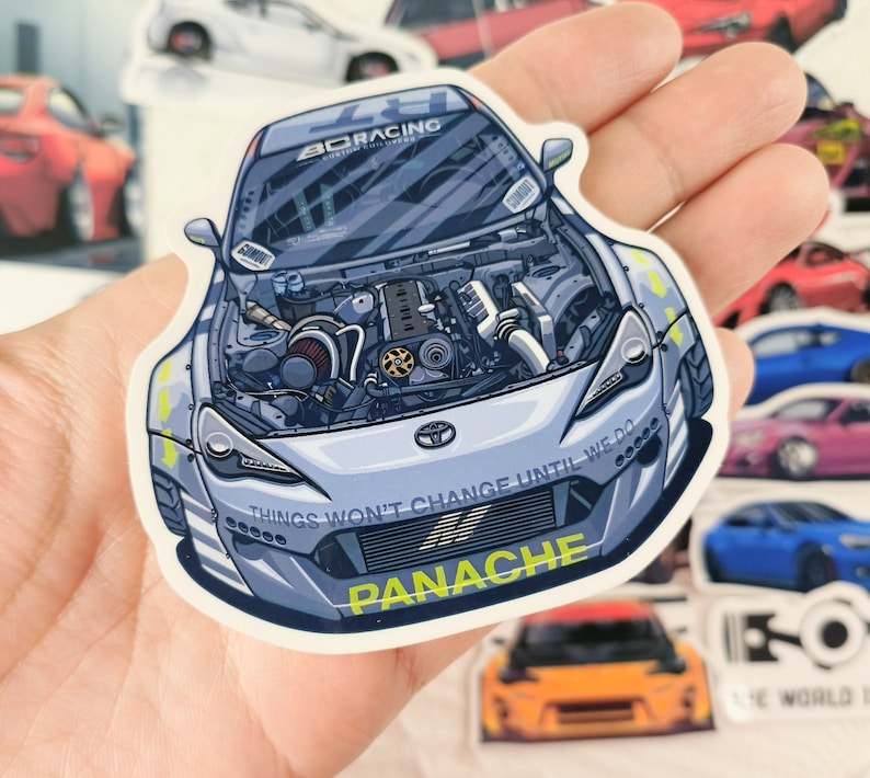 May include: A white car with a blue and black engine visible through the bonnet. The car has a black and yellow stripe on the front bumper and the words "Things won't change until we do" and "Panache" printed on the front.