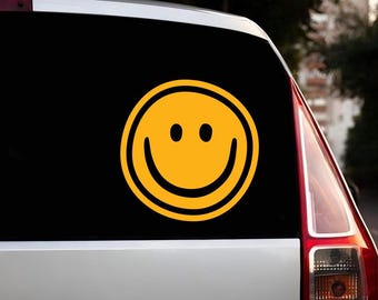 May include: A yellow smiley face sticker on a silver car.