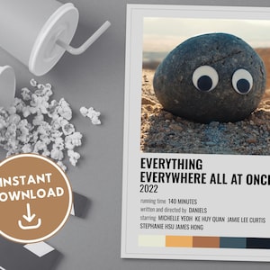 Może przedstawiać: Minimalistyczny plakat filmowy do filmu "Everything Everywhere All at Once" wydanego w 2022 roku. Plakat przedstawia szary kamień z wypukłymi oczami i paletę kolorów: biały, żółty, pomarańczowy, brązowy, szary i czarny.