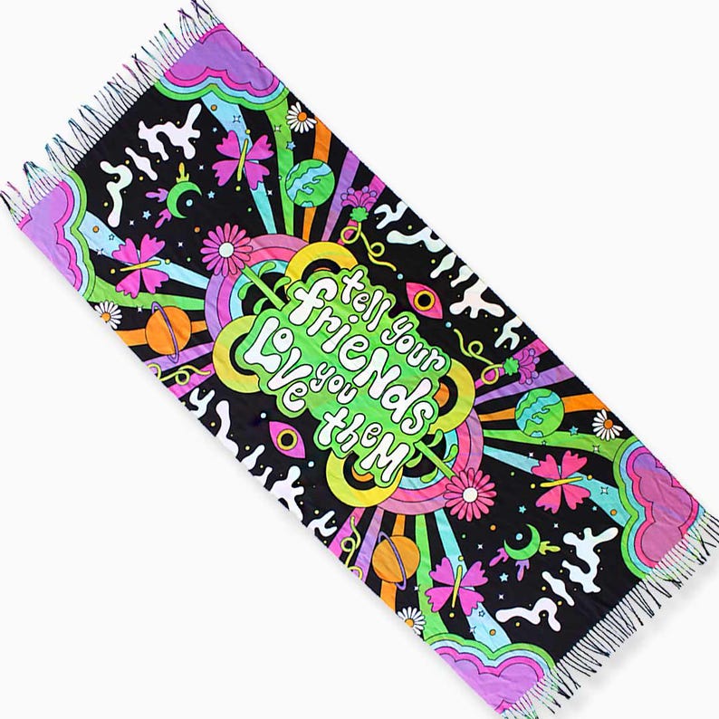 May include: A black and colorful tapestry with a fringed edge. The tapestry features a psychedelic design with planets, stars, butterflies, and flowers. The text "Tell your friends Love you them" is written in a colorful, whimsical font.