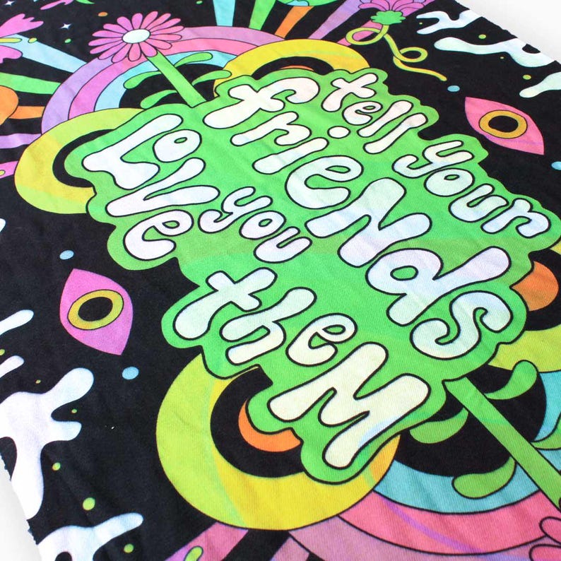 May include: A black fabric tapestry with a psychedelic design featuring a green, yellow, and white text that reads "Tell your friends you love them".