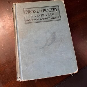 May include: A vintage book titled "Prose and Poetry Seventh Year" by Avery-Van Arsdale-Wilber. The book has a light blue cover with the title in a rectangular box. The book is slightly worn, with visible wear on the edges and corners.
