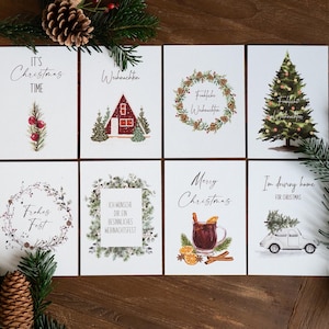 May include: A collection of eight Christmas-themed greeting cards with watercolor illustrations. The cards feature festive imagery like a Christmas tree, a cozy cabin, and holiday greetings such as "Merry Christmas" and "It's Christmas Time."