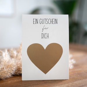 May include: A white card with the text "EIN GUTSCHEIN f&uuml;r DICH" and a gold heart in the center.