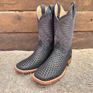 May include: A pair of black leather cowboy boots with a woven pattern. The boots have a pointed toe and a low heel.