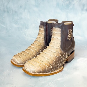 May include: A pair of brown leather ankle boots with a snakeskin pattern. The boots have a pointed toe and a low heel.