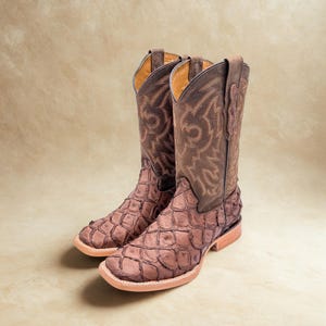 May include: A pair of brown western boots featuring a textured, scale-like pattern on the foot and a dark brown shaft with decorative tan stitching. The boots have a square toe, a stacked heel, and a light-colored welt with visible stitching.