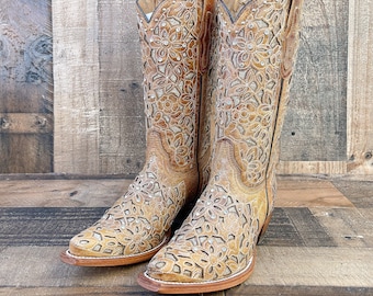 Könnte beinhalten: Ein Paar braune Leder-Cowgirl-Stiefel mit aufwendigen floralen Ausschnitten und Strasssteinen. Die Stiefel haben eine spitze Zehenpartie und einen niedrigen Absatz.