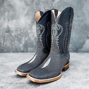 May include: A pair of black cowboy boots with a unique textured design. The boots have a pointed toe and a brown leather sole.