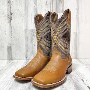 May include: A pair of brown leather cowboy boots with intricate stitching and a yellow and brown geometric pattern on the shaft. The boots have a square toe and a brown leather sole.